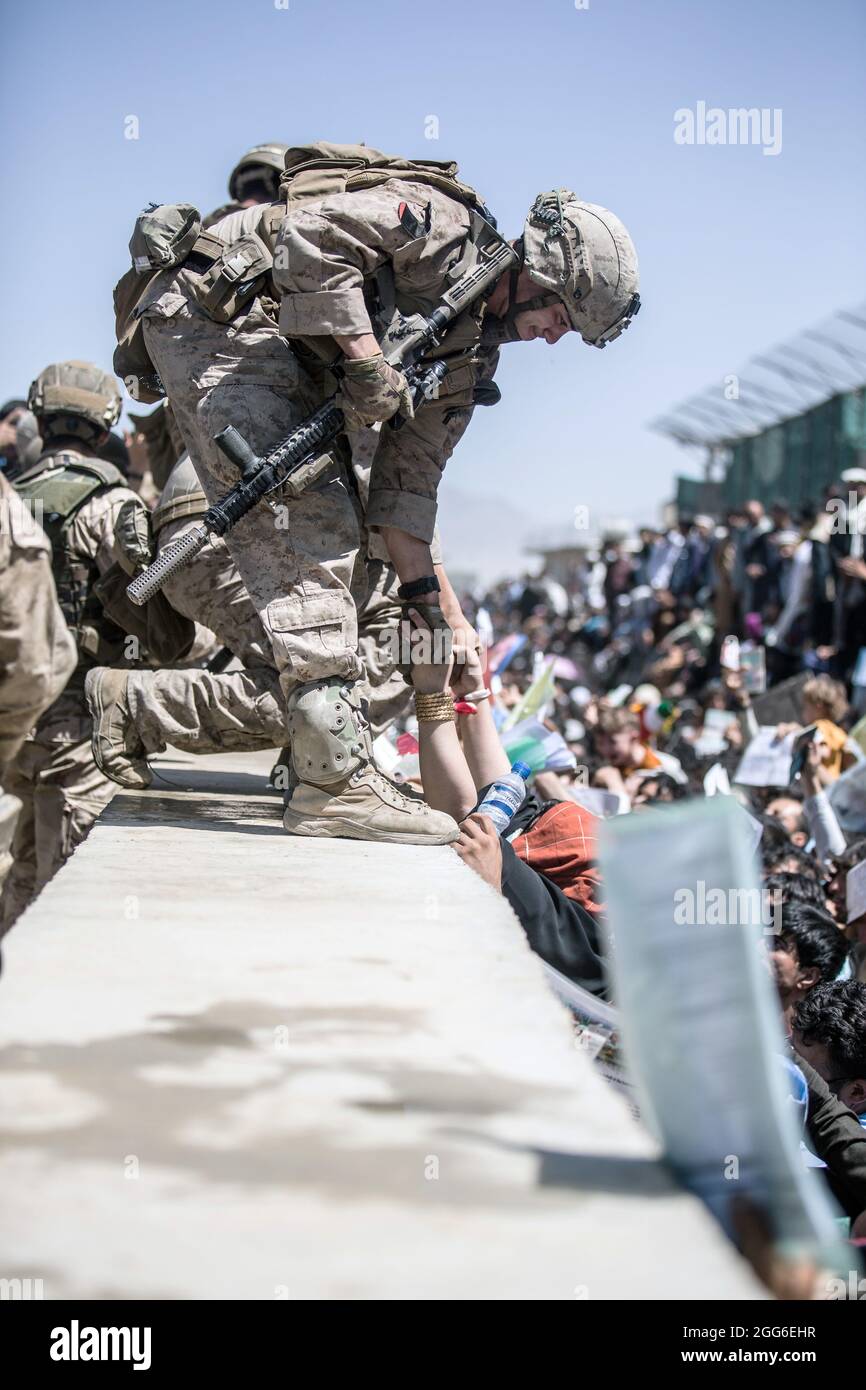 Kabul, Afghanistan. August 2021. Eine US-Marine mit dem Krisenreaktionsteam der Special Purpose Marine Air-Ground Task Force hebt eine Frau während der Operation Allies Refuge am 26. August 2021 in Kabul, Afghanistan, zur Evakuierung auf dem Hamid Karzai International Airport über die Sicherheitsmauer. Quelle: Planetpix/Alamy Live News Stockfoto