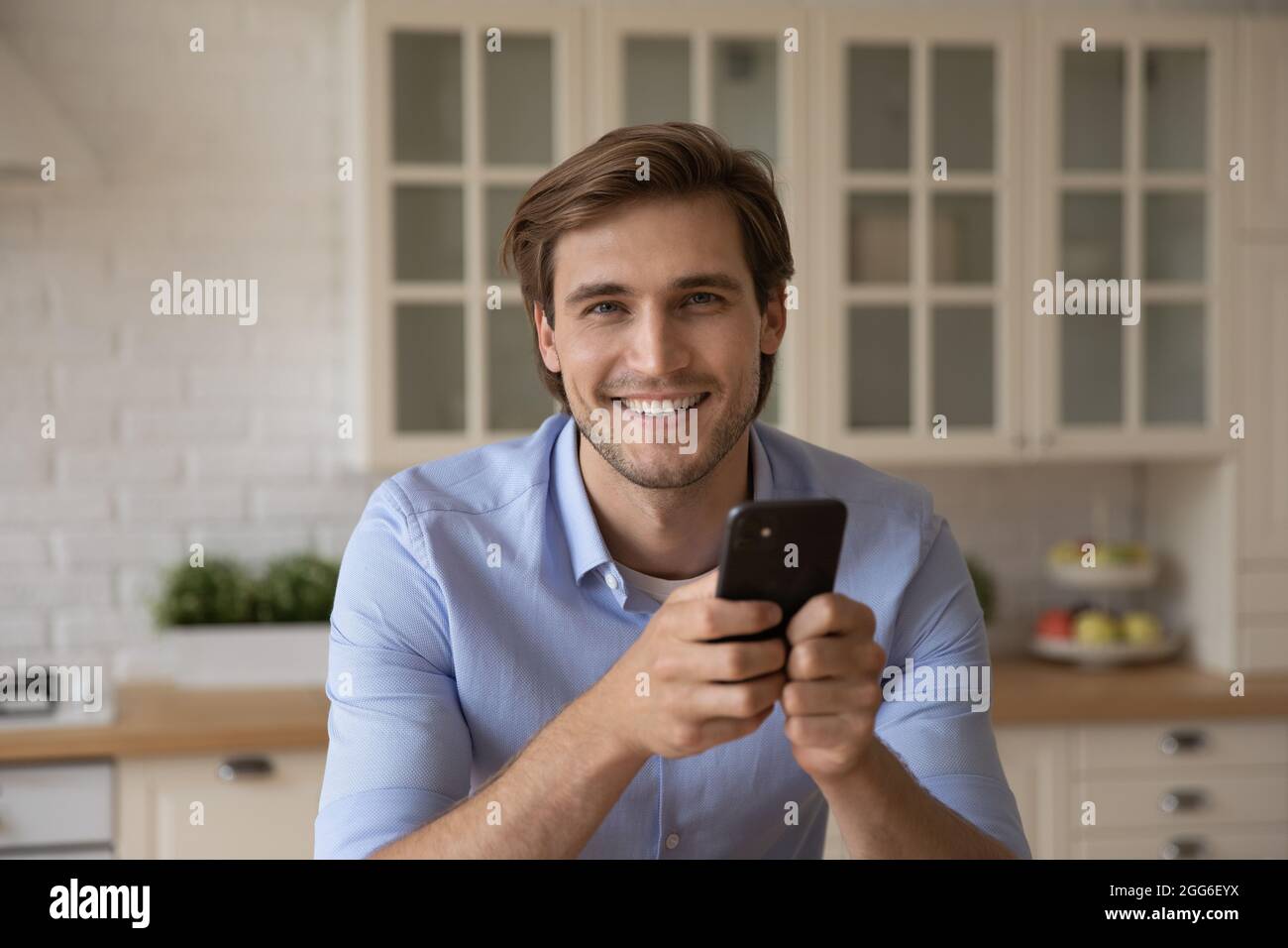 Porträt eines lächelnden jungen Mannes, der das Smartphone in den Händen hält. Stockfoto