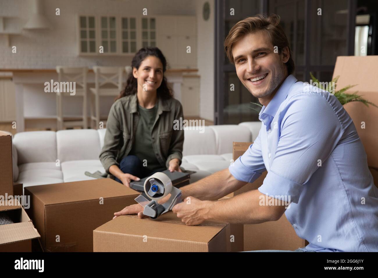Lächelndes junges Familienpaar, das Sachen in riesige Pappkartons verpackt. Stockfoto