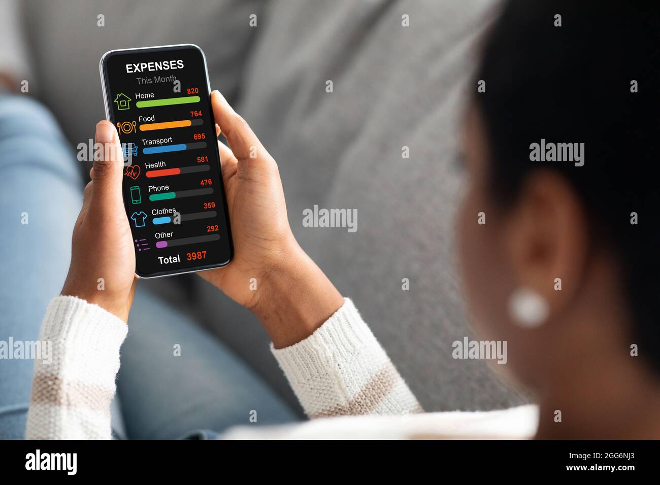Schwarze Frau mit Handy, die ihre monatlichen Spendings berechnet Stockfoto