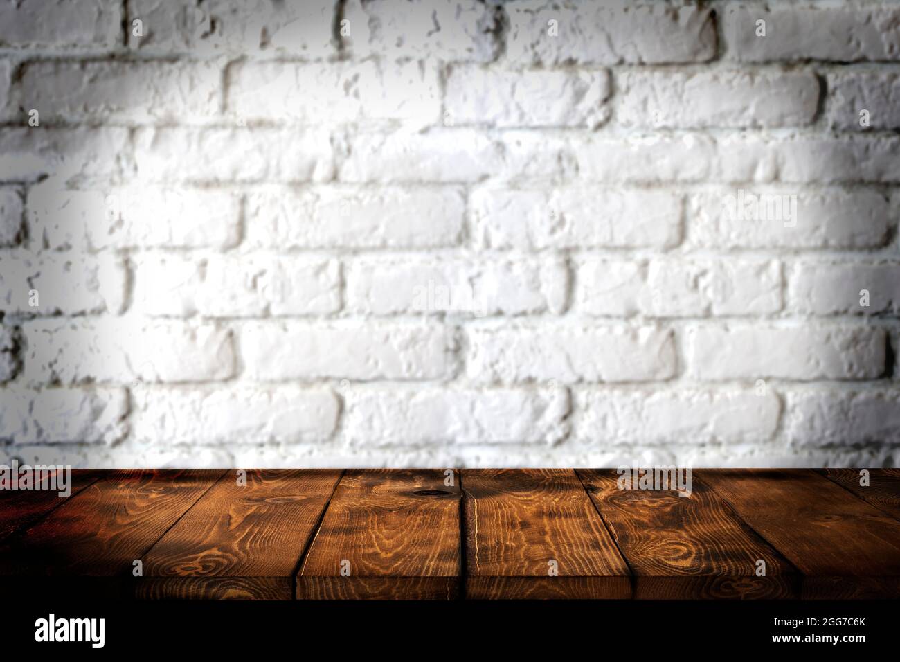 Hintergrund Holztisch und weiße Ziegelwand im Hintergrund, leere braune Holztischplatte für die Anzeige von Produkten in der Küche, im Geschäft, im Geschäft, im Café Stockfoto