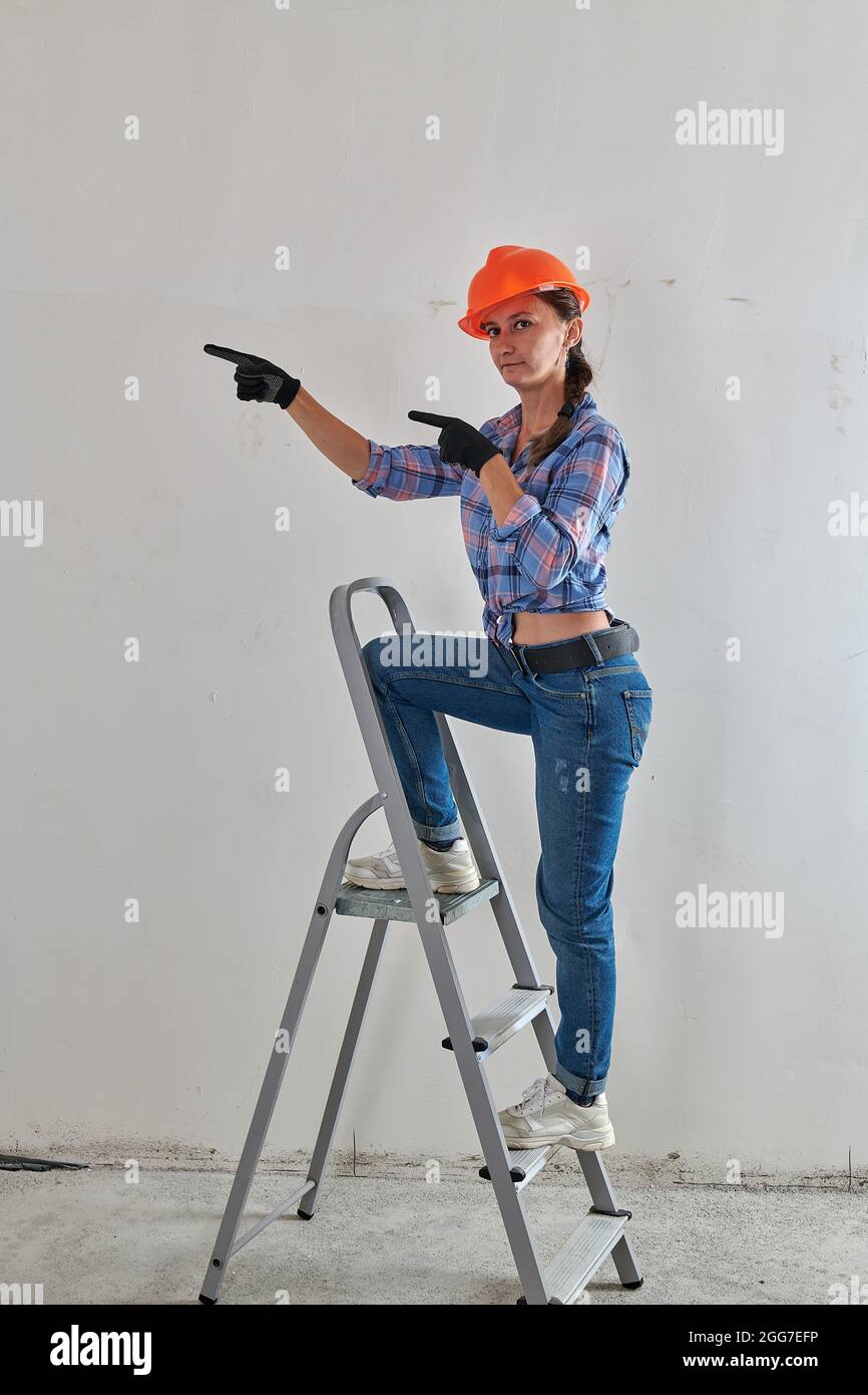 In einem karierten Hemd sitzt ein Vorarbeiter auf einer Stufenleiter Stockfoto