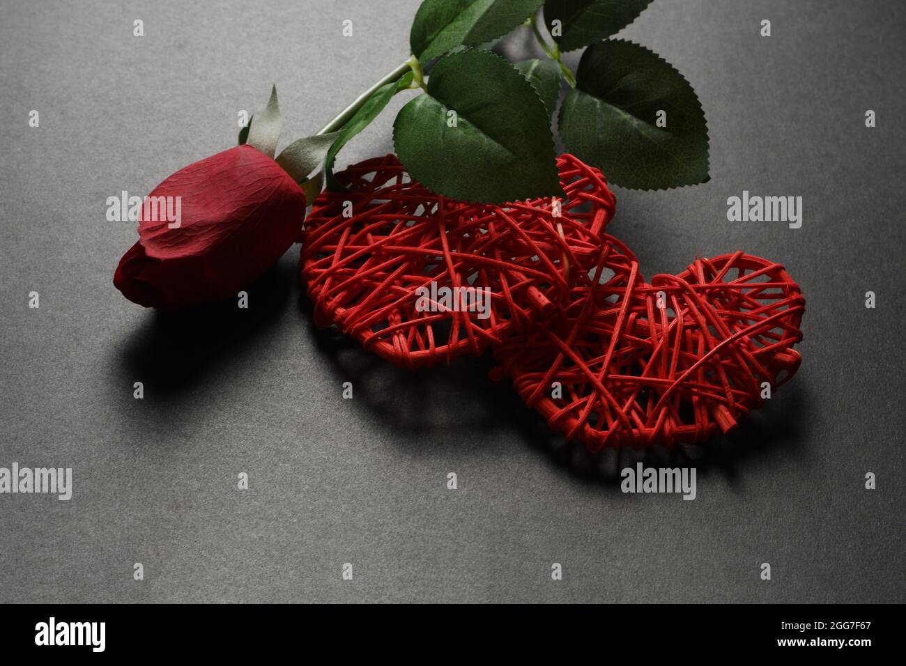 Zwei rote Herzen und eine rote Rose auf dunklem Grund. Stockfoto