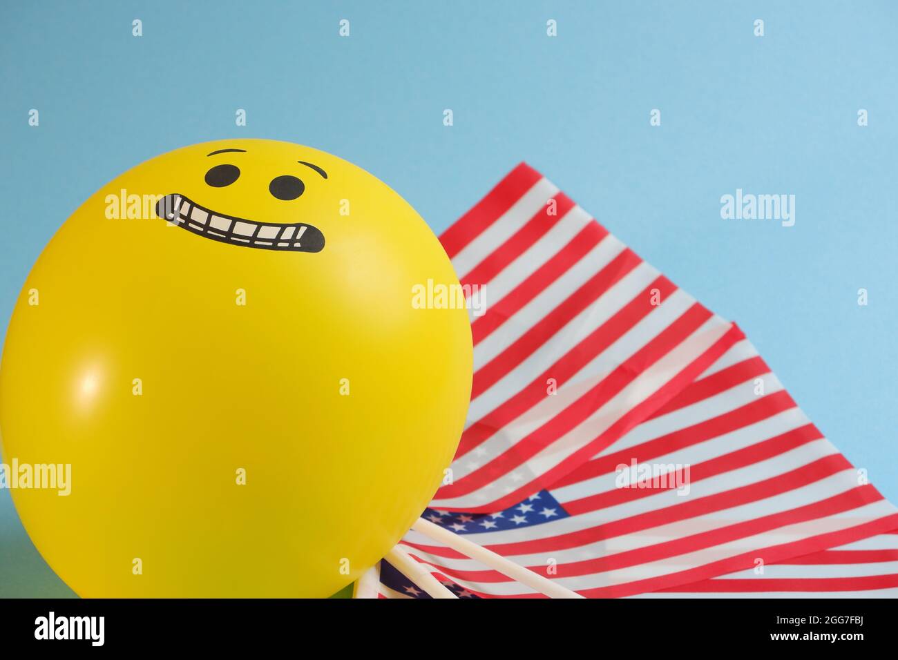 Gelbe Emoji-Ballons mit amerikanischen Flaggen auf blauem Hintergrund. Stockfoto