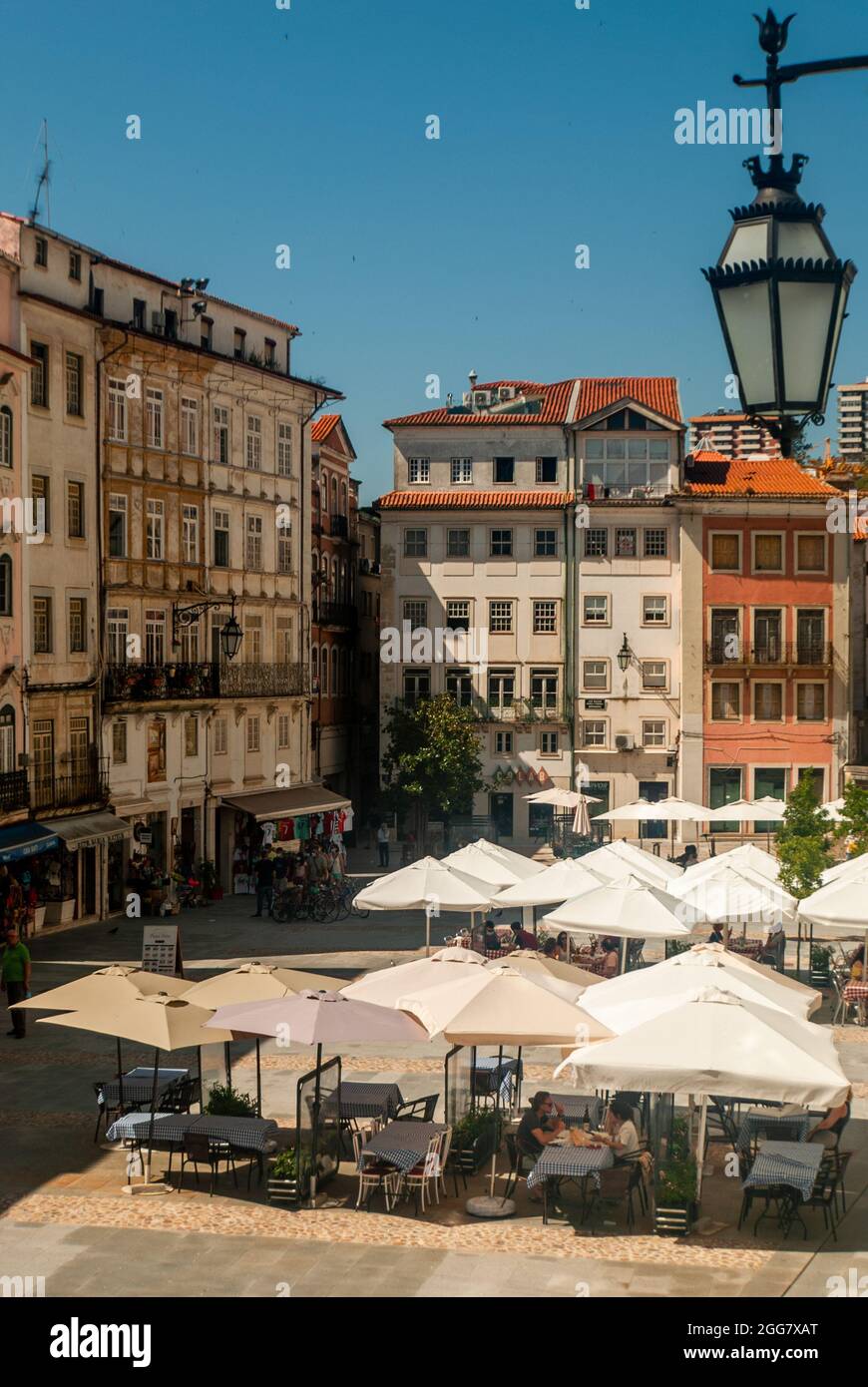 Commerce Square in Coimbra mit Restauranttischen und Sonnenschirmen an einem sonnigen Tag Mittagszeit - Portugal, vetisch, selektiver Fokus Stockfoto