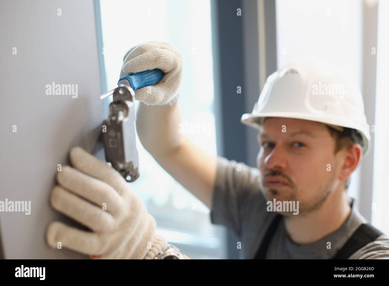 Mann dreht einen Schraubendreher in einem Schrank mit Armaturen Stockfoto