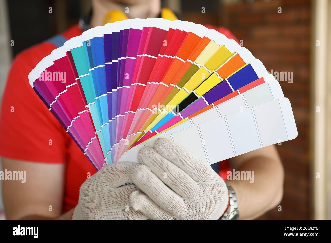 Ein Mann in Handschuhen zeigt Farbmuster zur Reparatur Stockfoto