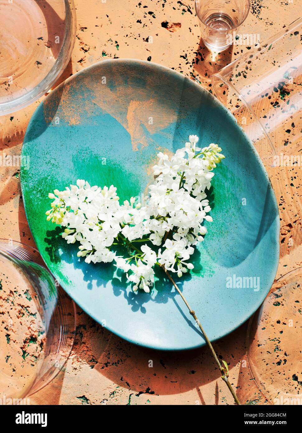 Blick von oben auf den weißen Fliederstrauß auf Stein gemalten Teller Stockfoto