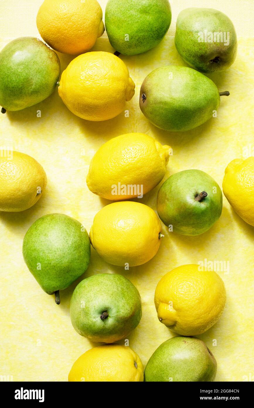 Ansicht von oben auf Zitronen und Birnen auf gelbem Tischtuch Stockfoto