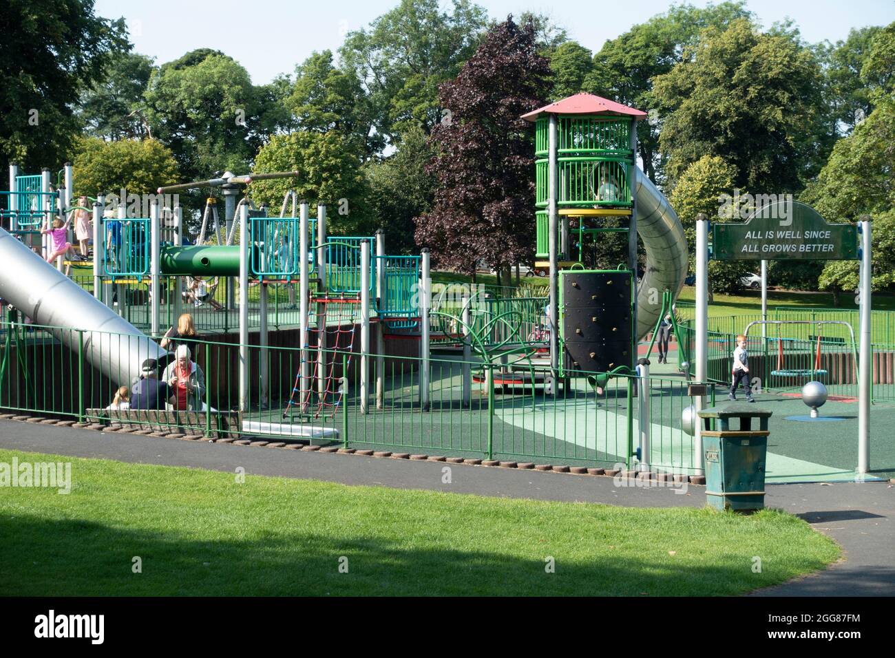 Teil des Kinderspielparks im Pittencrieff Park, Dunfermline mit Kindern und Erwachsenen. Über dem Eingangstor: 'Alles ist gut, da alles bette wächst Stockfoto