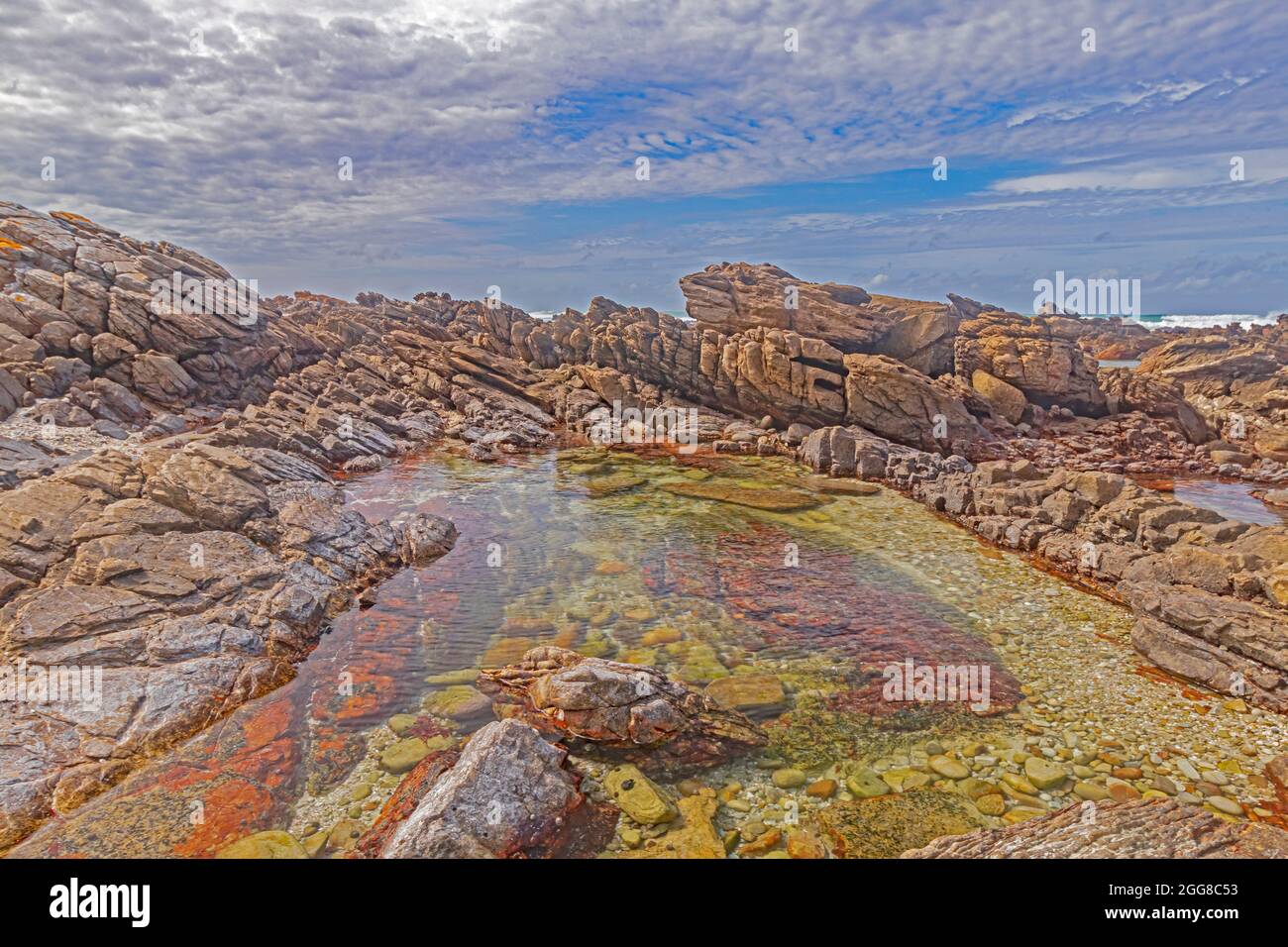 Felsformationen mit Gezeitenbecken am Ufer des Kap Agulhas in Südafrika, dem südlichsten Punkt des afrikanischen Kontinents. Stockfoto