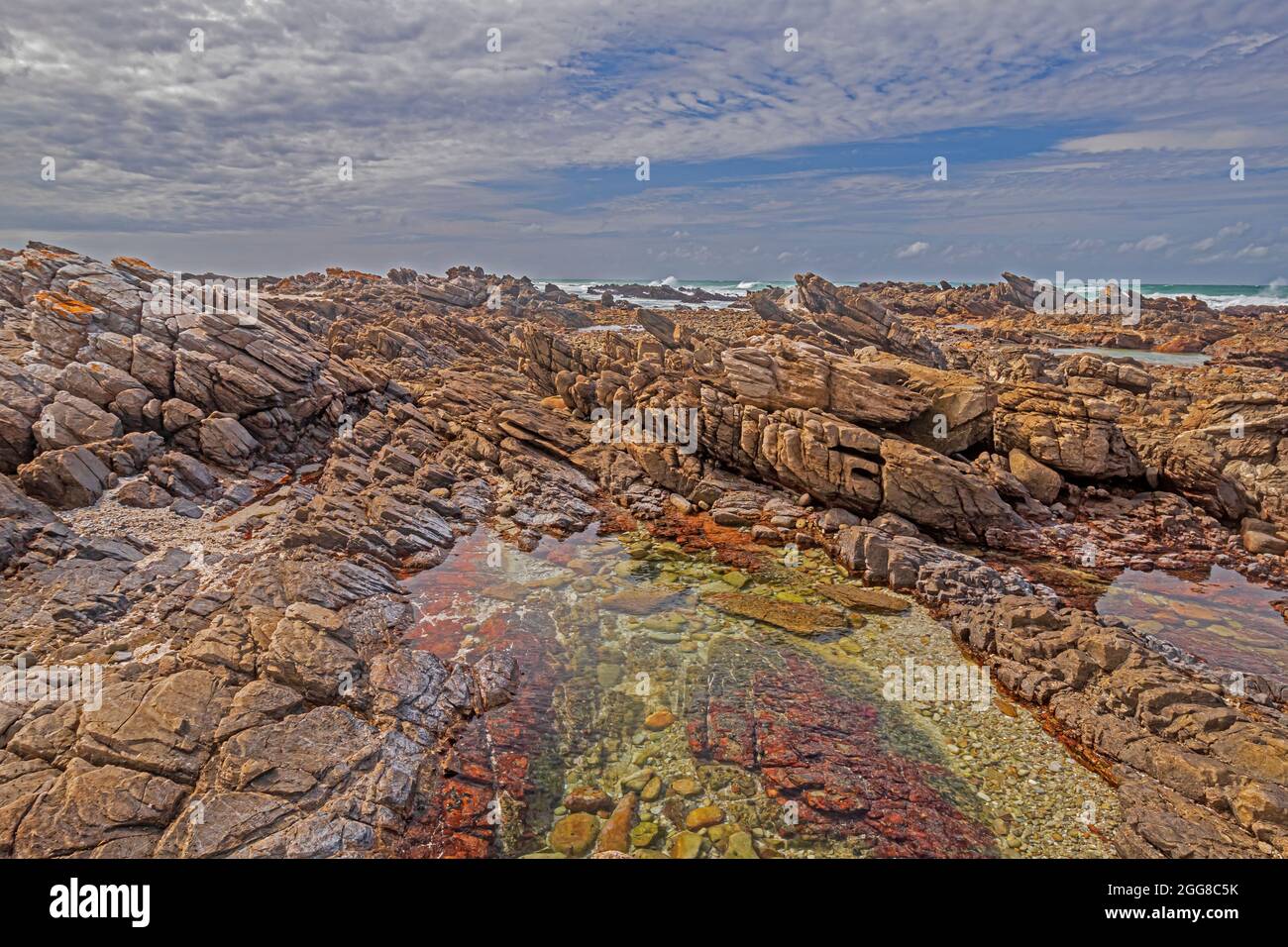 Felsformationen mit Gezeitenbecken am Ufer des Kap Agulhas in Südafrika, dem südlichsten Punkt des afrikanischen Kontinents. Stockfoto