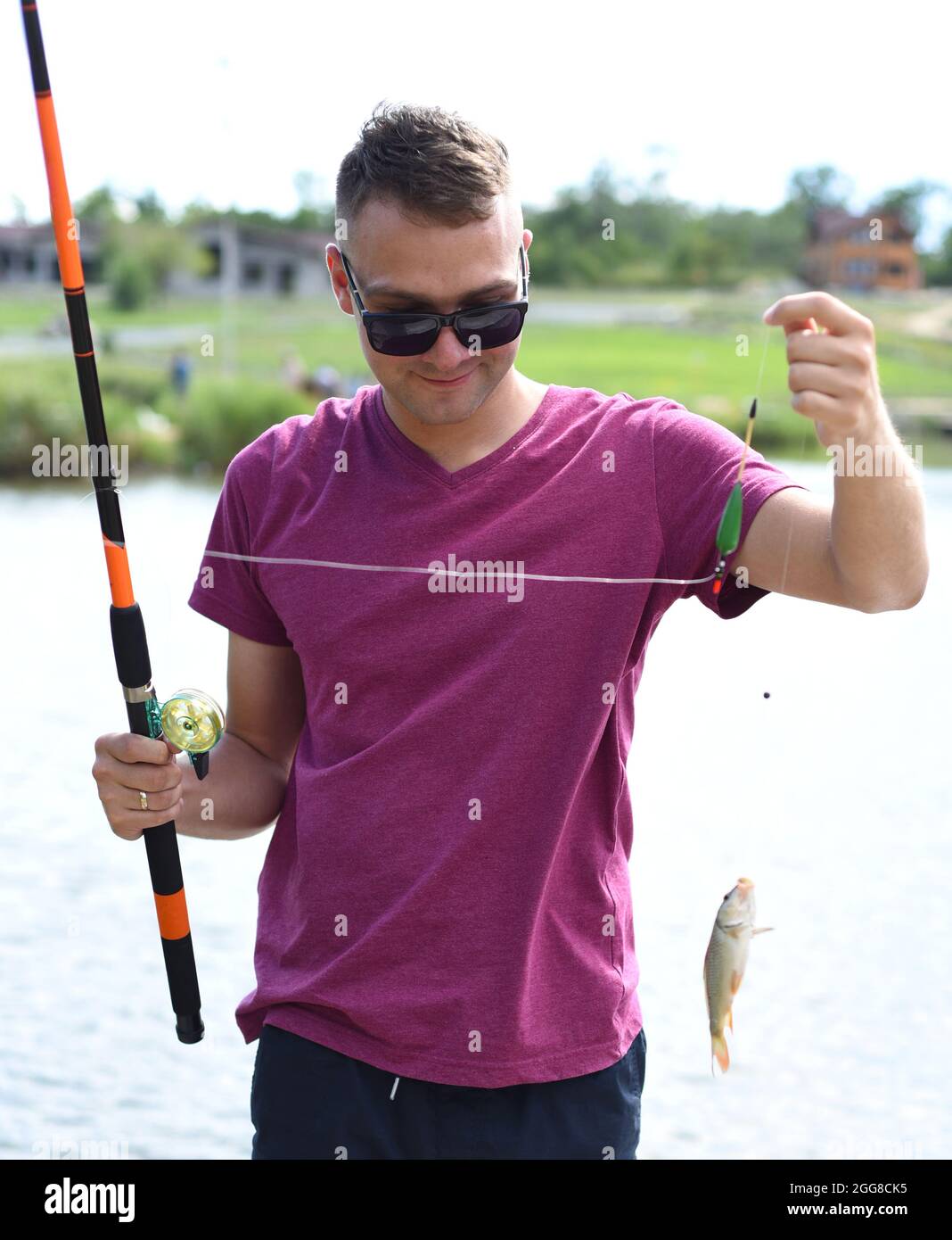Junger Fischer hält Karauschen auf Angelrute an einem Teich Stockfoto