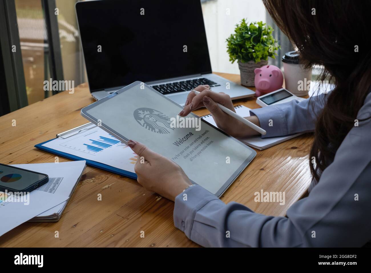 Chiang Mai, Thailand - 26. August 2021 : Frau sitzt im Starbucks Café und Starbucks Logo auf dem Tablet Stockfoto