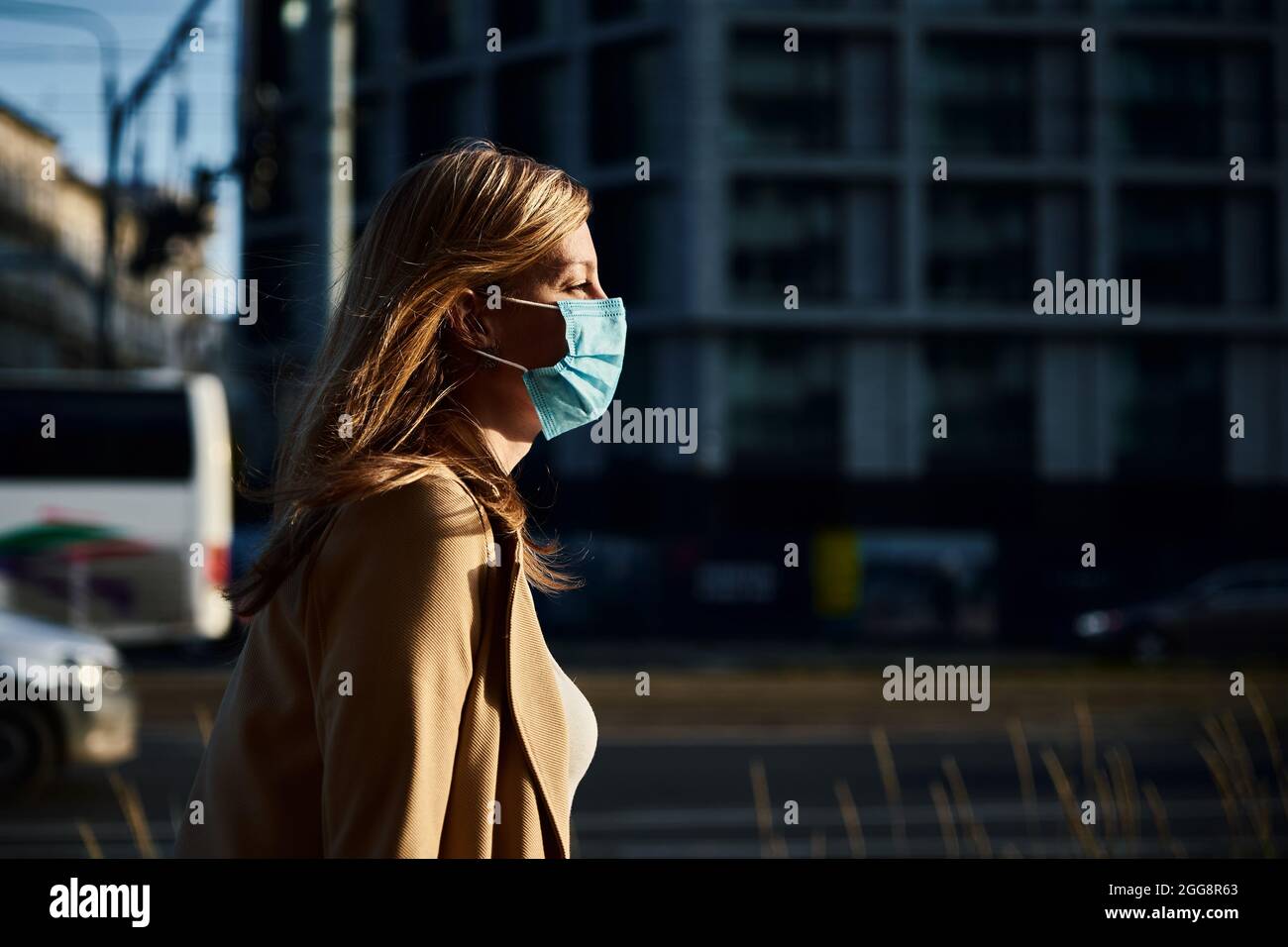 Schöne kaukasische Frau trägt medizinische Schutzmaske in der Stadt Straße. Porträt einer Frau aus dem Tausendjahrtausend. Soziale Distanz und Schutz vor Coronavirus Stockfoto