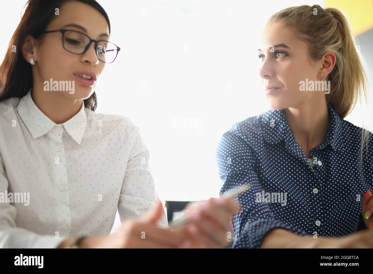 Schöne Frau hört Kollegen im Büro zu Stockfoto