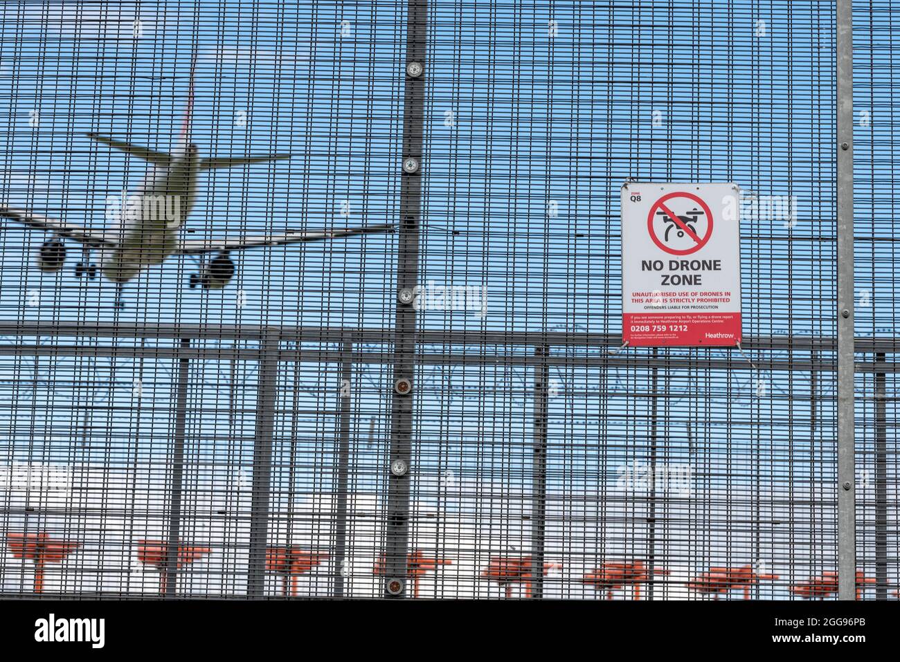 Kein Drohnenschild am Flughafen London Heathrow, Großbritannien, mit einem Flugzeug, das dahinter landet. Warnschild Umzäunung. Kein unbefugtes Fliegen mit einer Drohne Stockfoto