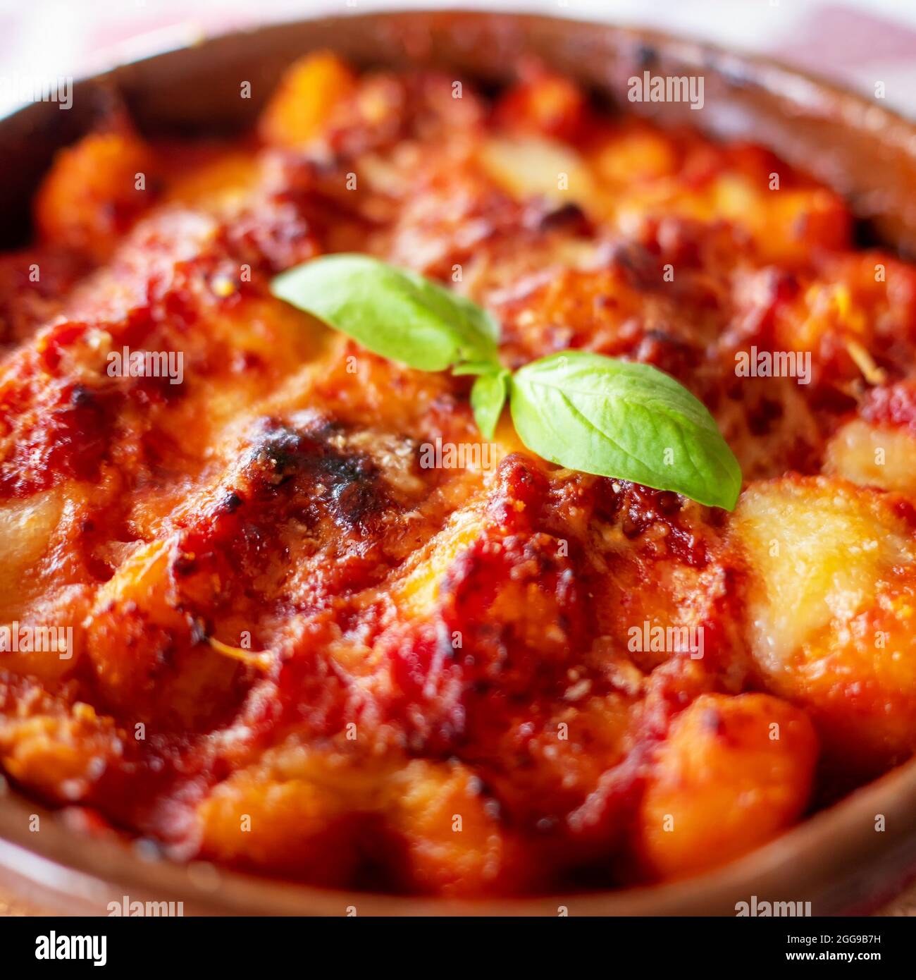 Gnocchi alla Sorrentina, italienische Kartoffelknödel in Tomatensauce, mit Mozzarella-Käse in einer Terrakotta-Schale geriebt. Selektiver Fokus. Stockfoto
