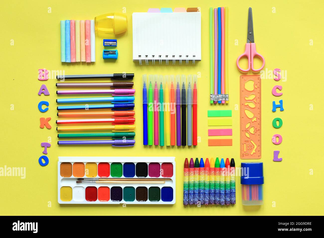 Malzubehör auf farbigem Hintergrund. Set der ersten Grader auf gelbem Hintergrund. Büromaterial in einem Layout auf einem gelben. Flaches Layout Stockfoto