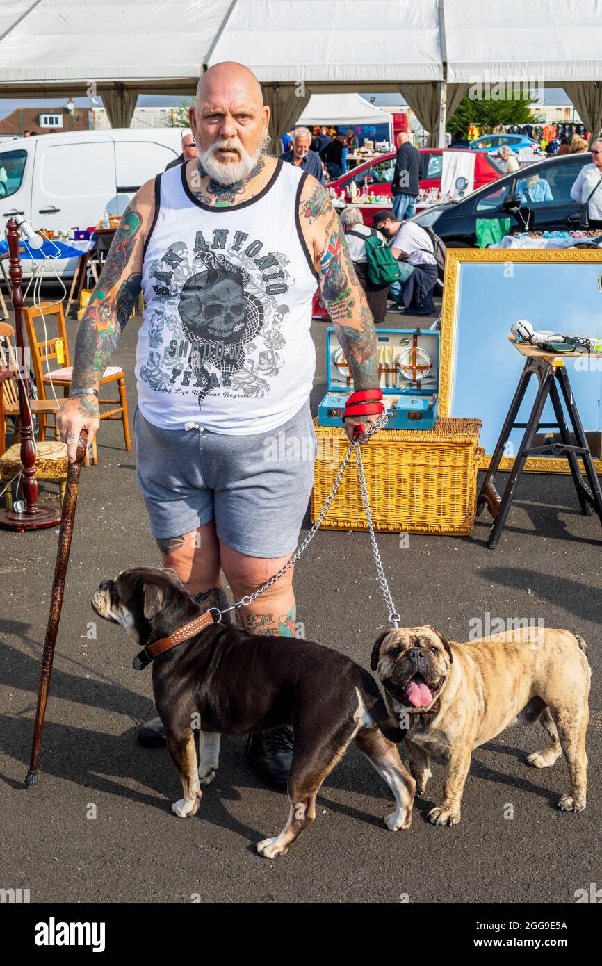 Porträt eines Mannes mit Tattoos und seiner zwei Mischhunde beim Autobootverkauf und auf dem Freiluftmarkt, ayr Racecourse, ayr, schottland, großbritannien Stockfoto