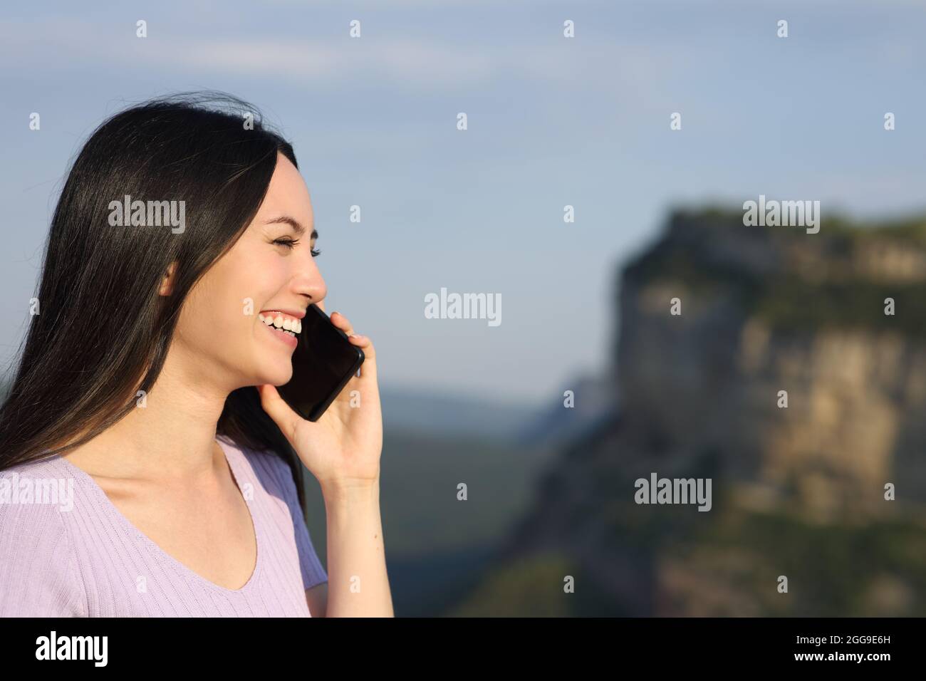 Asiatische Frau im Gespräch auf dem Handy lächelt in den Bergen Stockfoto