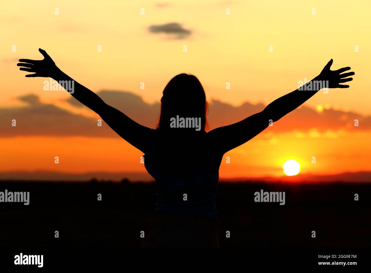 Rückansicht Porträt einer Frau Silhouette feiert Strecken Arme bei Sonnenuntergang Stockfoto
