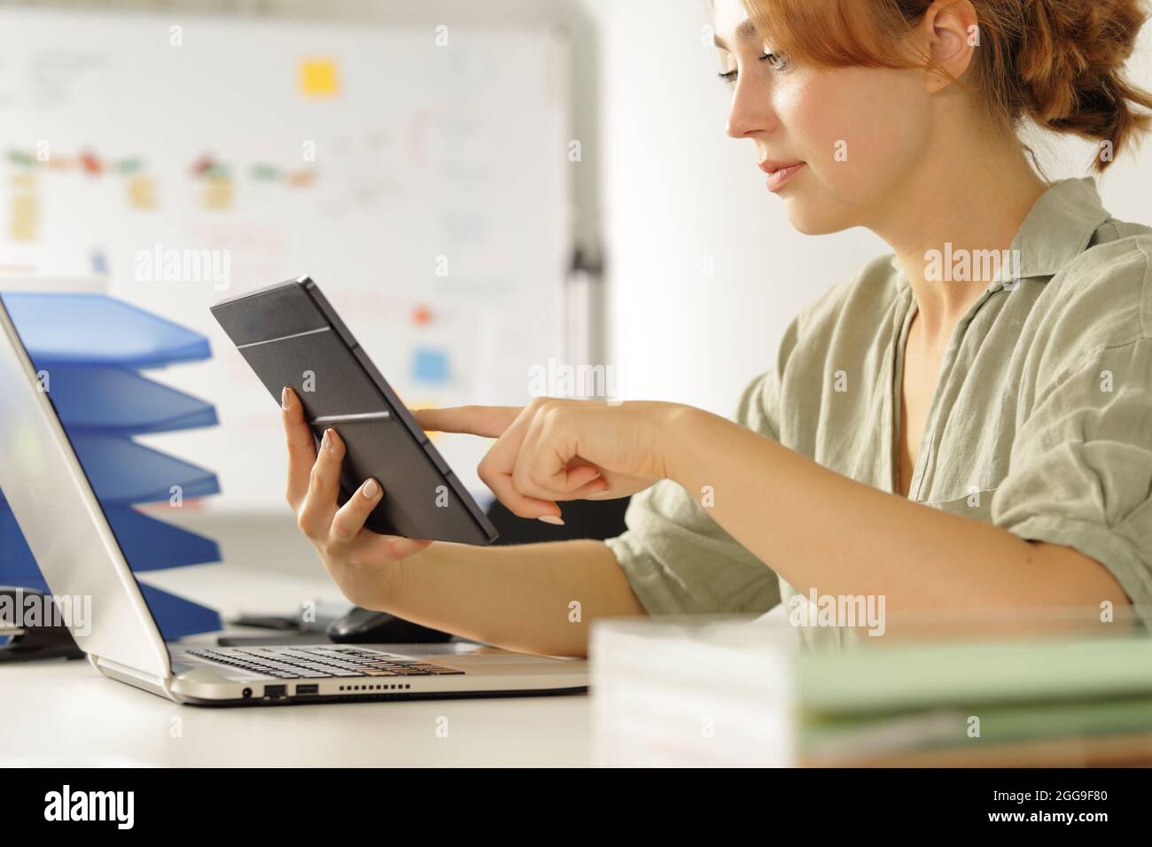 Konzentrierte Frau, die im Büro arbeitet und den Inhalt des Tablets überprüft Stockfoto