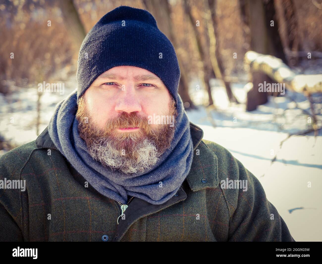 Im Freien Porträt eines erwachsenen bärtigen europäischen Mannes im Winter. Bärtiger Mann, der sich auf einem Winterspaziergang im verschneiten Wald entspannt, eine ehrliche Aufnahme, eine Lifestyle-Szene Stockfoto