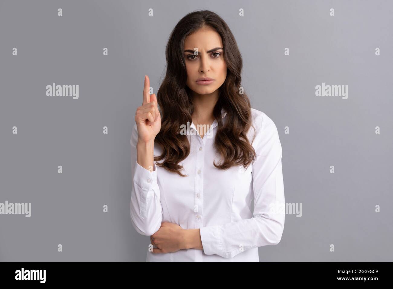 Runzelte Frau Führungskraft zeigen den Finger auf grauen Hintergrund, Idee Stockfoto