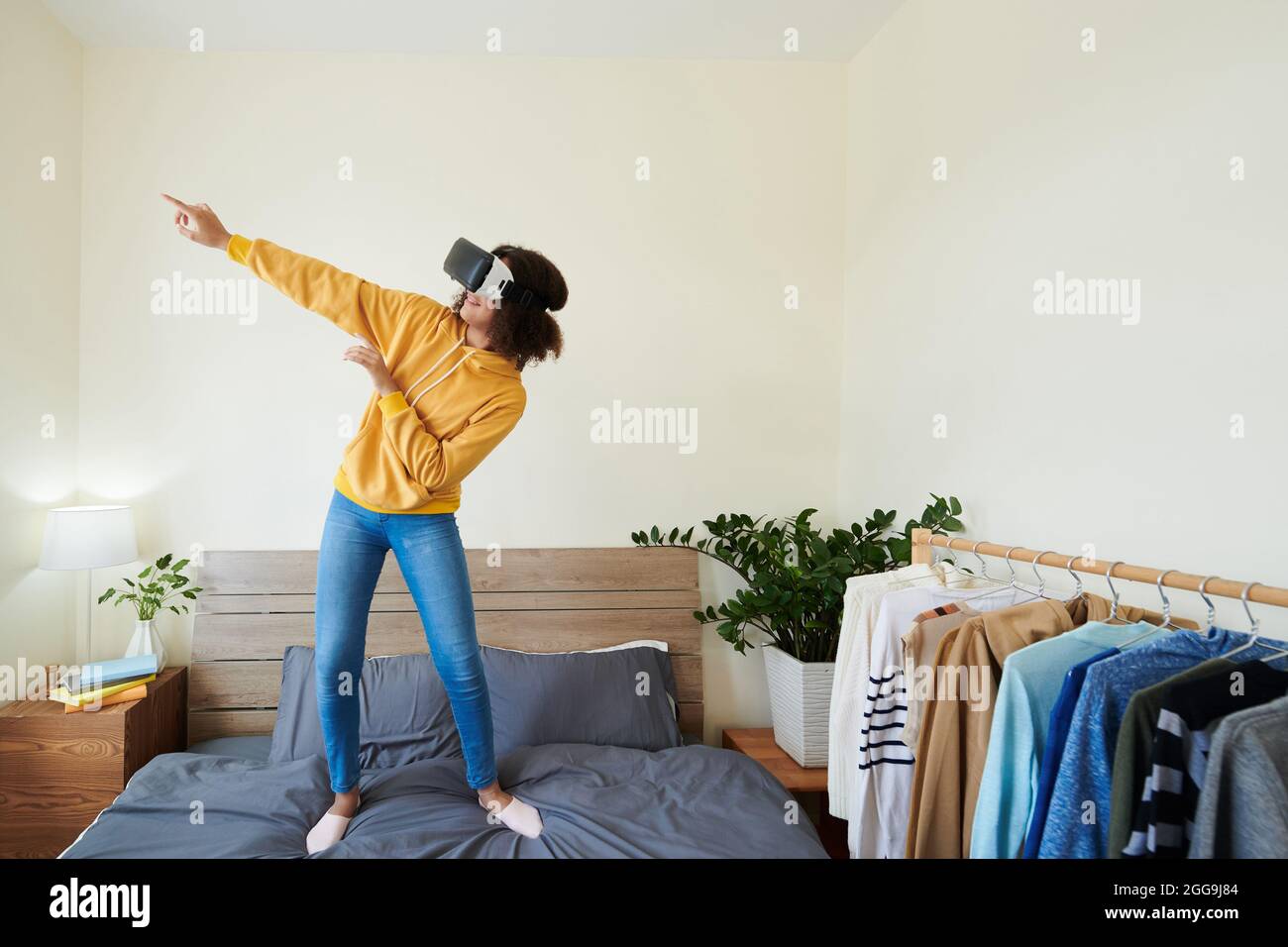 Fröhliche Teenager-Mädchen in Virtual-Reality-Brille tanzen, wenn Videospiel zu Hause spielen Stockfoto
