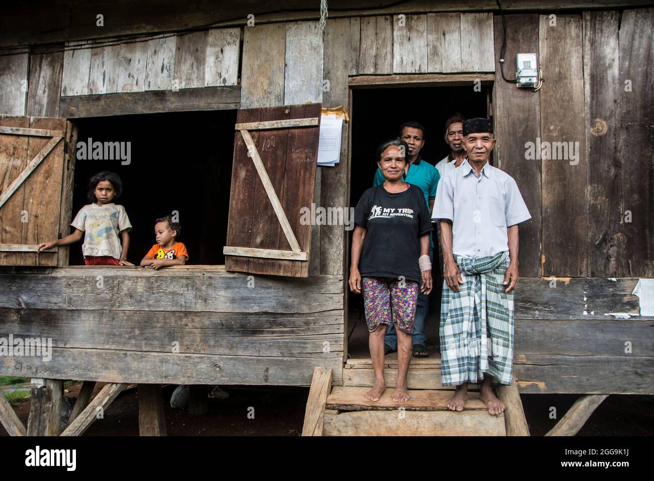 Familienmitglieder posieren auf den Stufen ihres traditionellen Manggarai-Hauses in der Nähe von Ruteng auf der Insel Flores Stockfoto