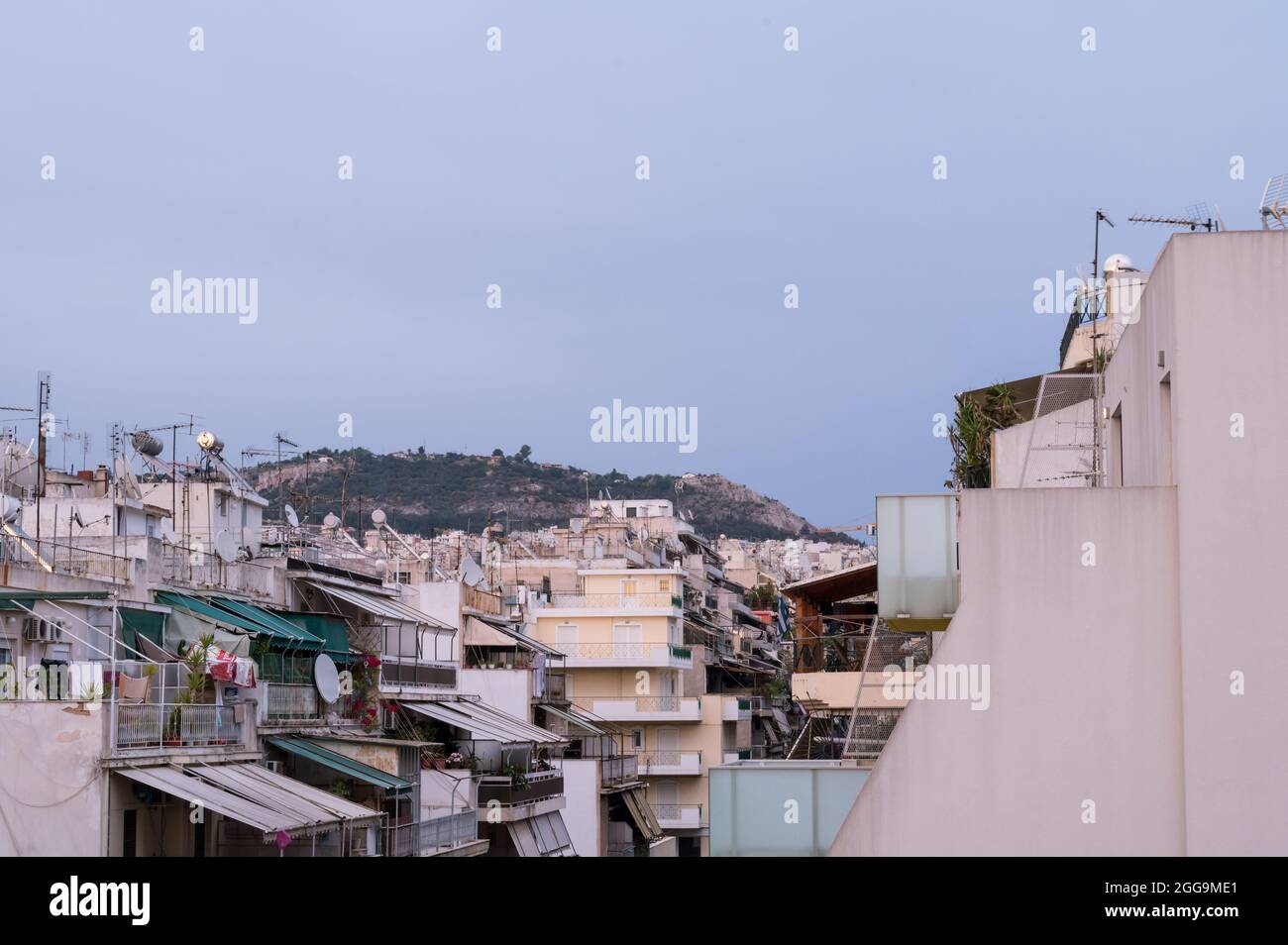 Stadtbild eines Wohngebiets in Athen bei Abendlicht. Stadtarchitektur. Berg im Hintergrund. Stockfoto