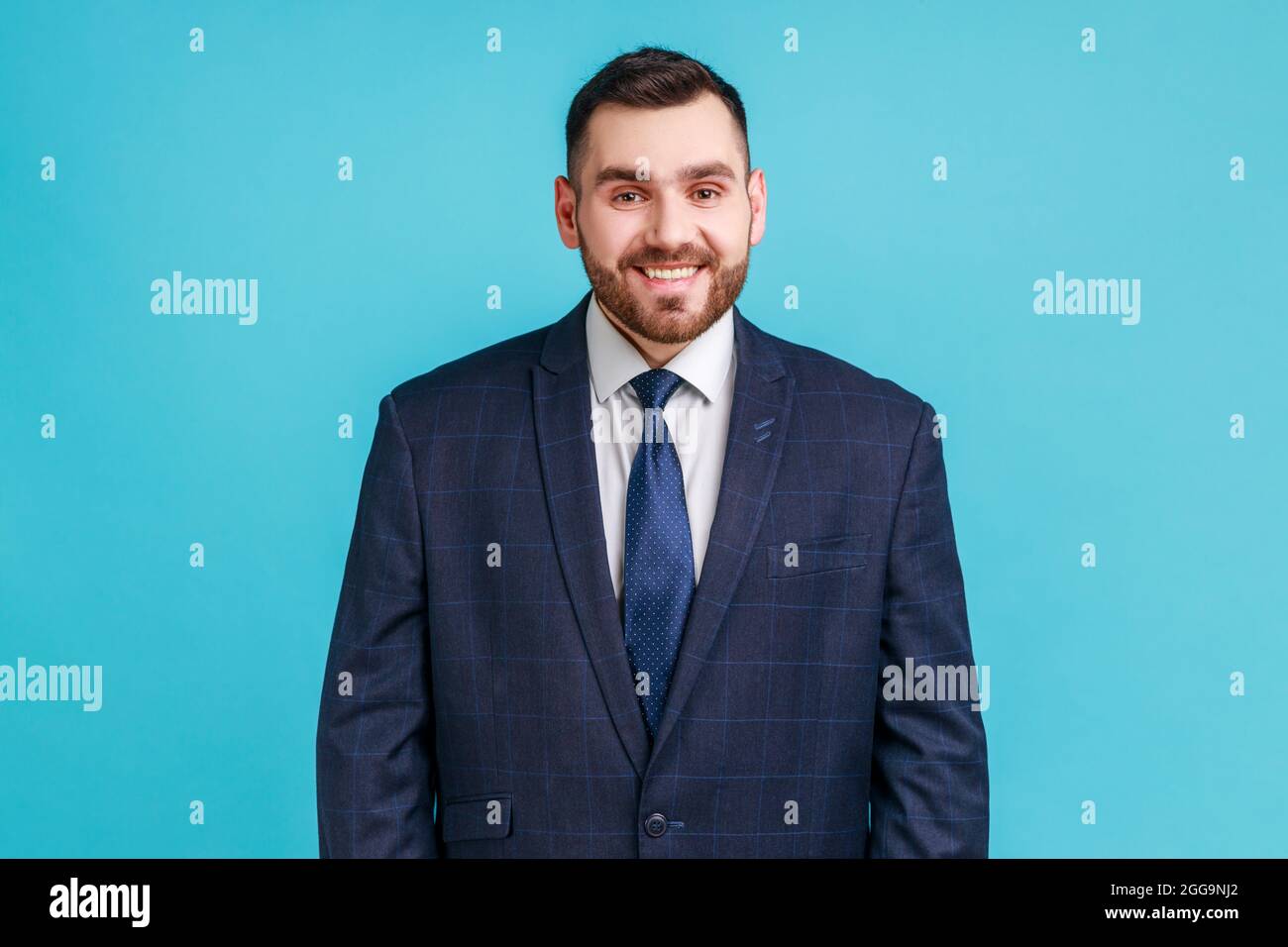 Porträt eines jungen erwachsenen, hübschen Geschäftsmannes im offiziellen Anzug, der mit einem toothy Lächeln auf die Kamera blickt und positive Emotionen und Glück zum Ausdruck bringt Stockfoto