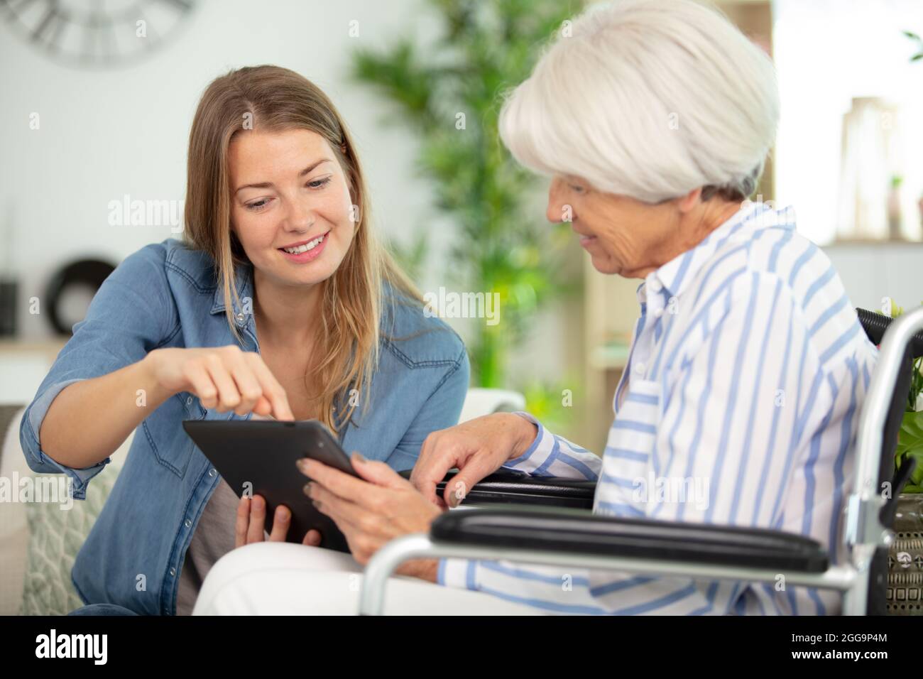 Gesundheitsbesucherin und eine ältere Frau mit Tablet Stockfoto