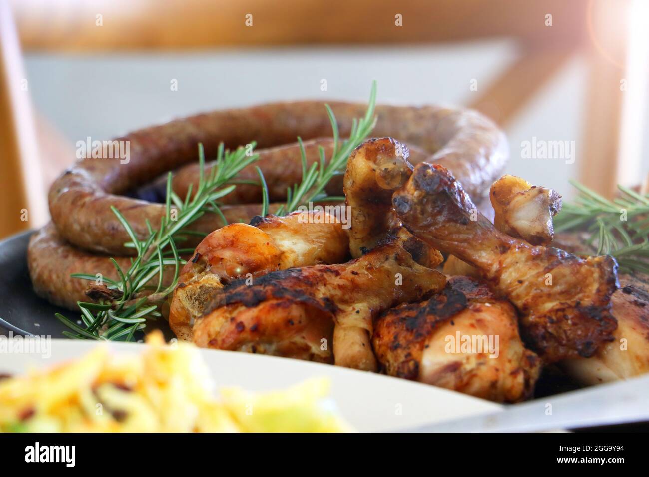 Grillen Sie Fleisch, Huhn und Boerewors auf Teller, fertig zum Essen mit Salat und Mais Stockfoto