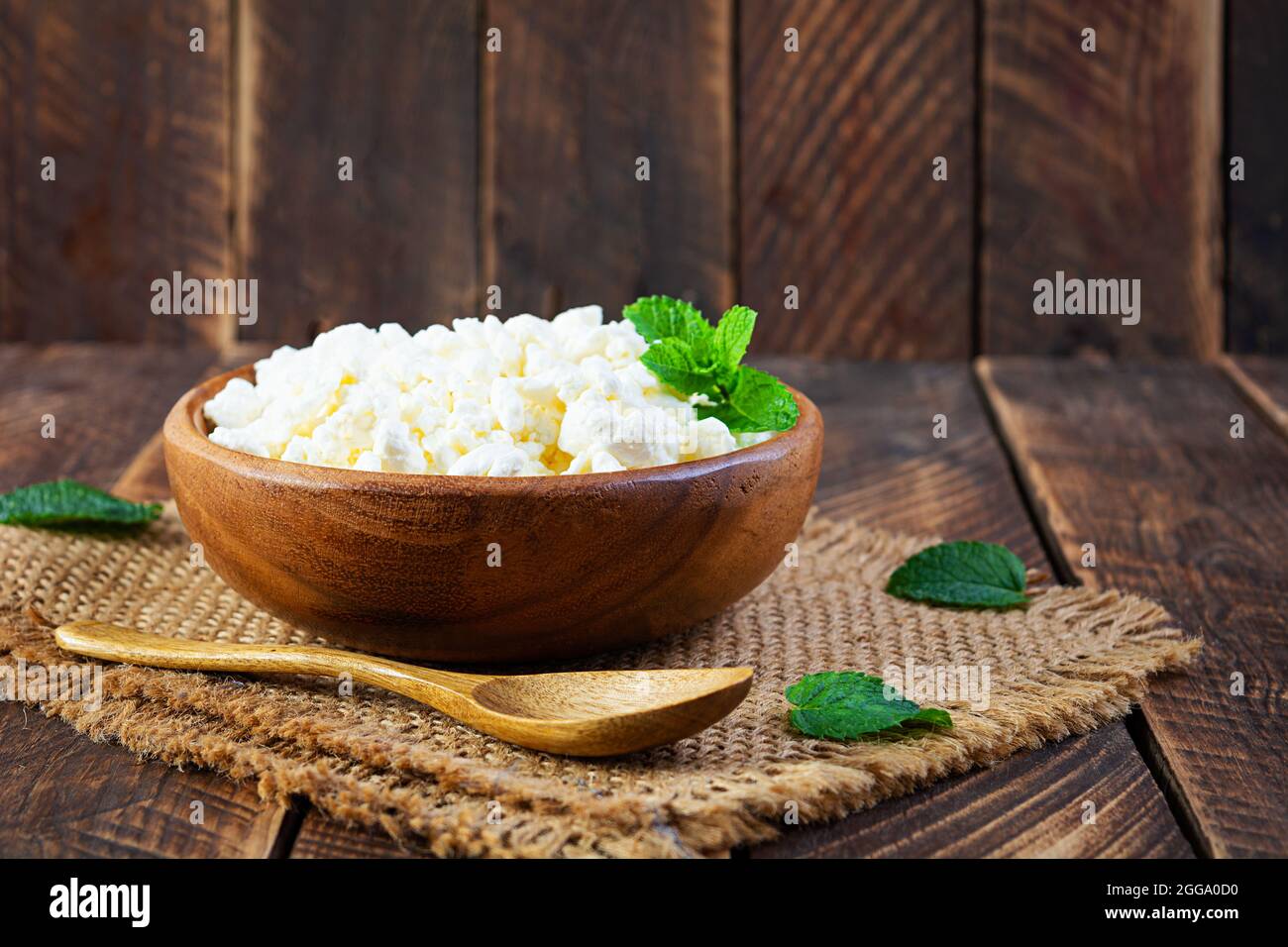 Schüssel mit Hüttenkäse auf Holzhintergrund. Frischer hausgemachter Hüttenkäse Stockfoto