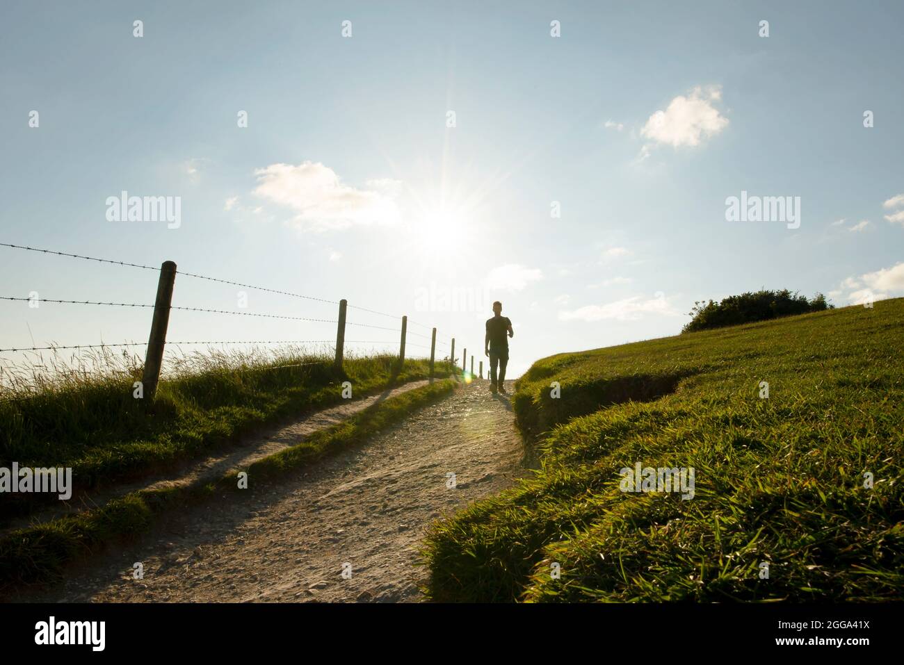 Silhouette eines Mannes, der den Fußweg zur Lulworth Cove entlang geht, der ikonischen Landschaft der Jurassic Coast. Dorset, Großbritannien. August 2021 Stockfoto