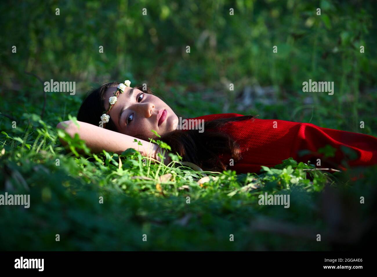 Junges Mädchen von 12 mit rotem Kleid und einem Kranz, entspannen im Freien Stockfoto