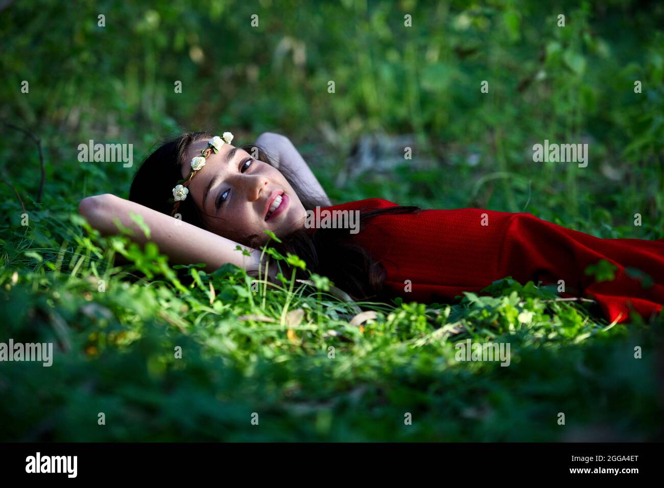Junges Mädchen von 12 mit rotem Kleid und einem Kranz, entspannen im Freien Stockfoto
