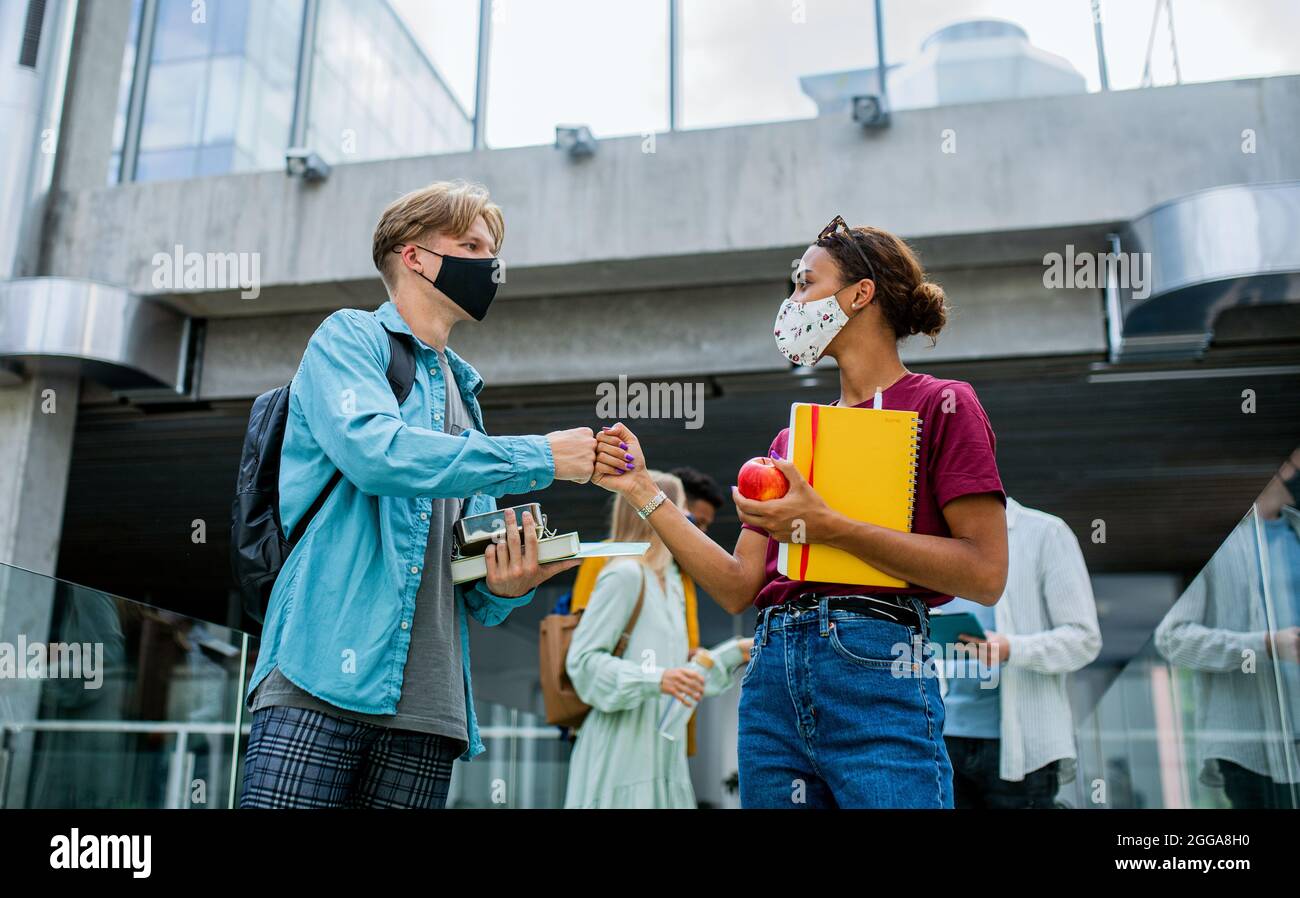 Studenten stehen und grüßen drinnen, Coronavirus und zurück zum normalen Konzept. Stockfoto