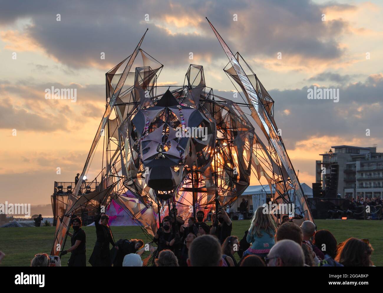 The Hatchling, eine gigantische Marionette, die im Rahmen ihres zweitägigen Debüts vom Sonnenuntergang auf Plymouth Hoe beleuchtet wird. Die riesige Puppe und das Straßentheater Stockfoto