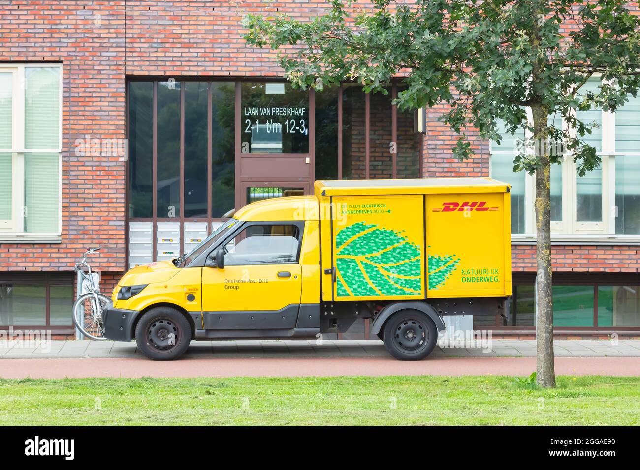 Arnhem, Niederlande - 21. Juli 2021: Elektrischer DHL-Postkurierwagen vor einem Mehrfamilienhaus in Arnhem, Niederlande Stockfoto