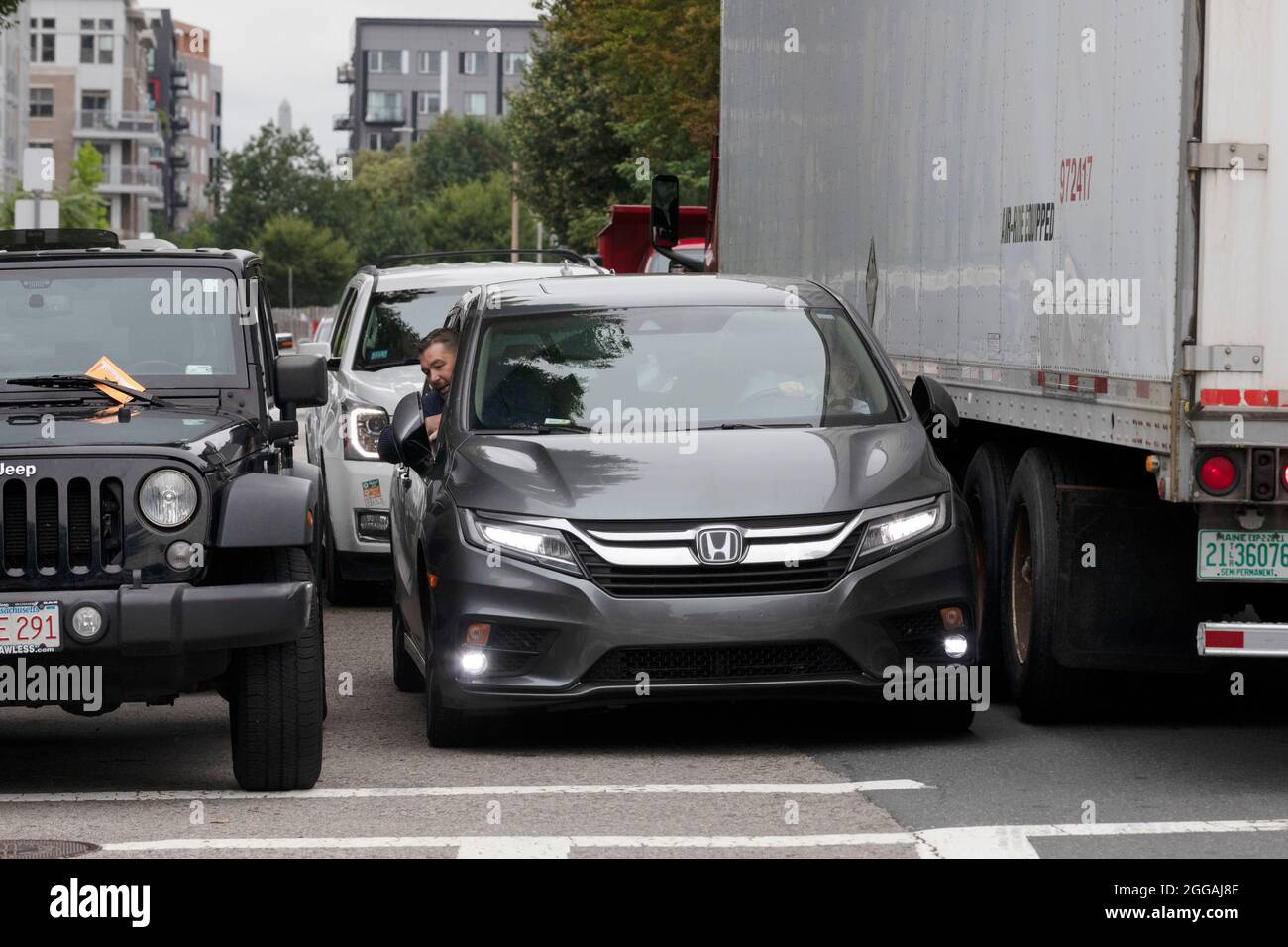 Auto versucht, durch große LKW geparkte Fahrzeuge Autos zu bekommen Stockfoto