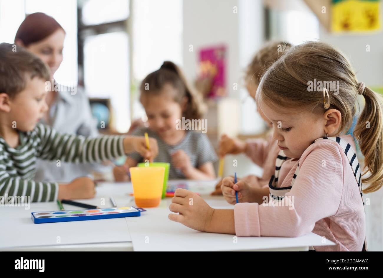 Gruppe von kleinen Kindergarten-Kinder mit Lehrer drinnen im Klassenzimmer, Malerei. Stockfoto