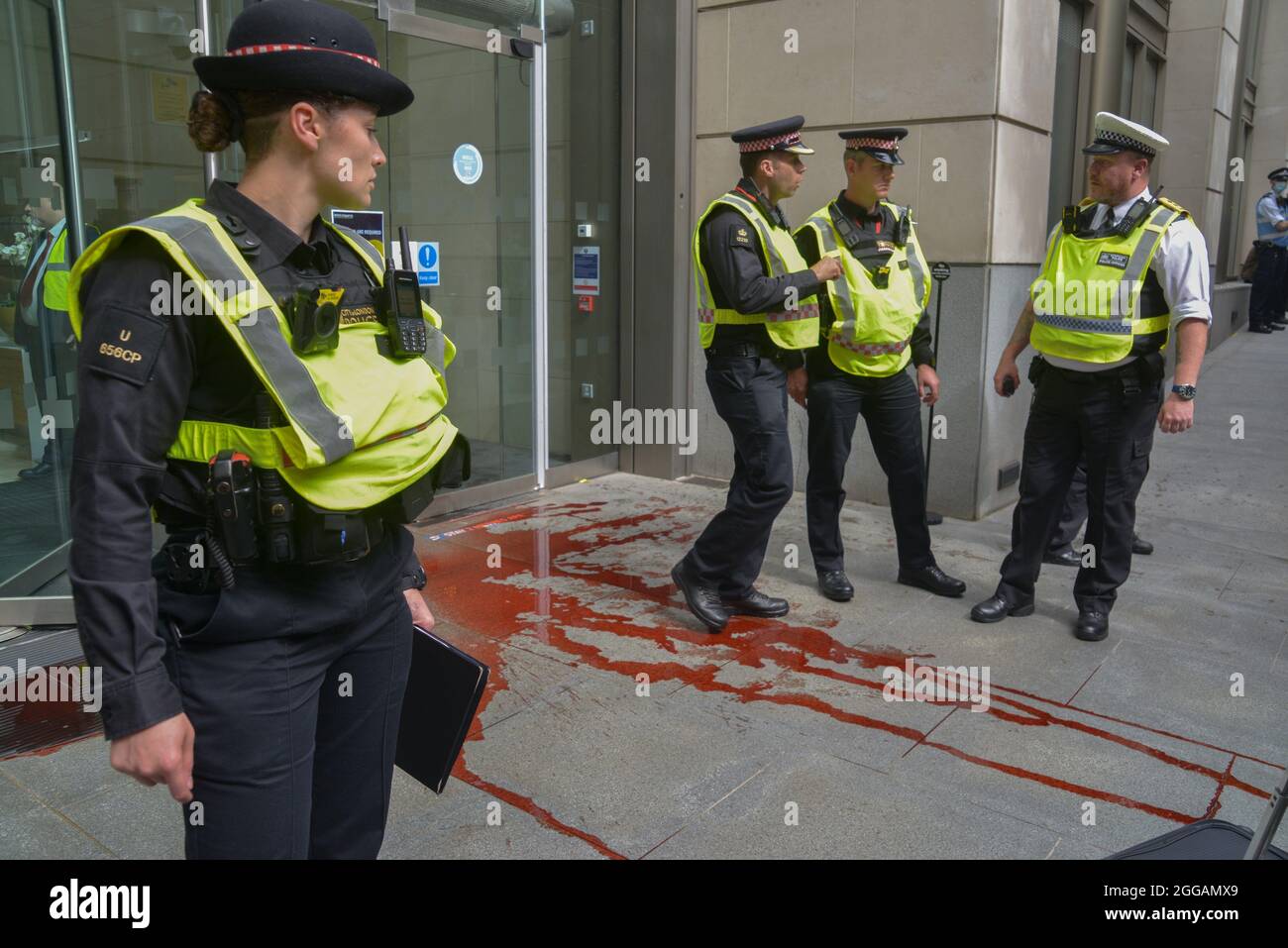 Der Aktivist der Extinction Rebellion warf während des Blutgeldmarsches rote Farbe vor ein Bürogebäude im Finanzdistrikt der City of London. Stockfoto