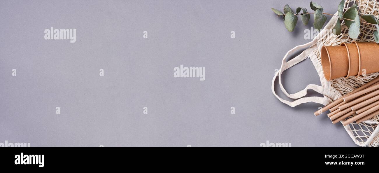 Trinkröhrchen Trinkhalme aus Papier und Maisstärke, Netzmarktbeutel und leere Pappkaffee auf trendigem grauen Hintergrund. Keine Abfälle und Plas Stockfoto