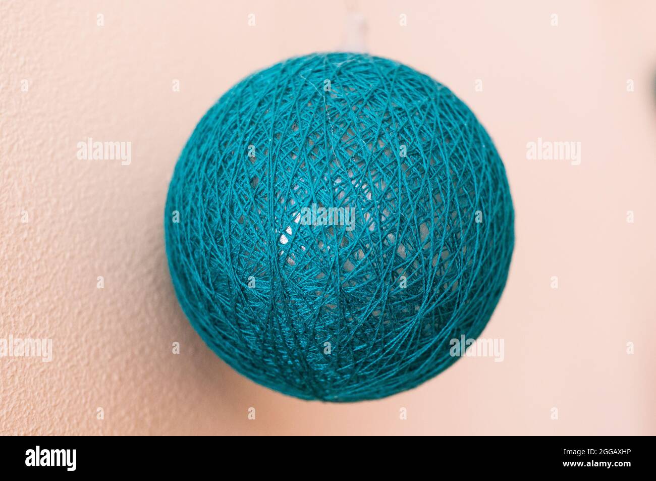 Nahaufnahme einer handgefertigten türkisfarbenen Kugel aus Fäden und einem Ballon Stockfoto