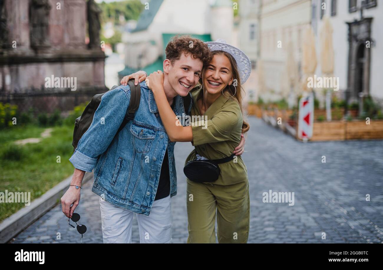 Fröhliches junges Paar draußen auf der Straße auf einem Stadtausflug, zu Fuß und mit Blick auf die Kamera. Stockfoto