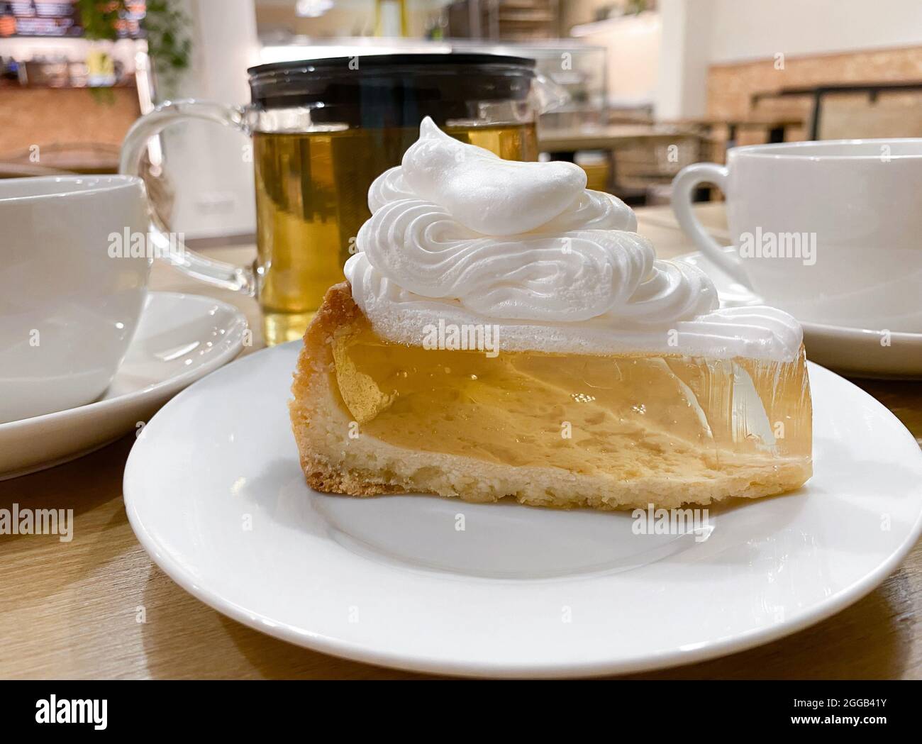 Nahaufnahme des Stückes transparenter Gelatinekuchen-Shortbread-Teig mit Baiser-Creme auf dem Tisch im Café. Stockfoto