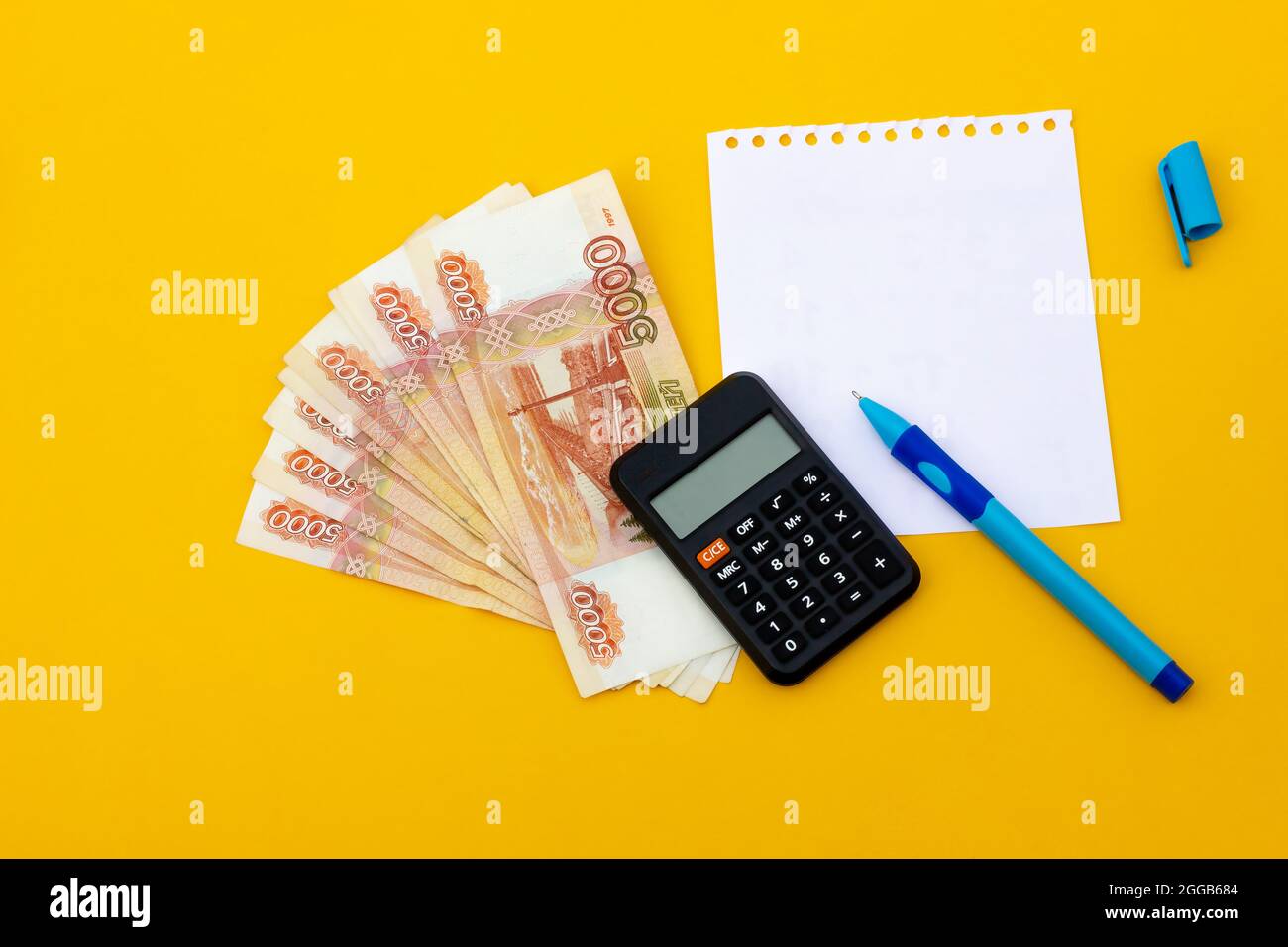 Russische Banknoten mit Notizbuch und Stift auf gelbem Hintergrund. Geschäftskonzept Stockfoto